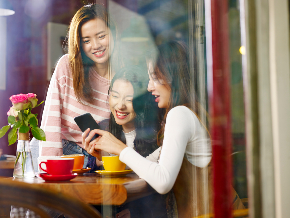 three women watching a video on a mobile phone