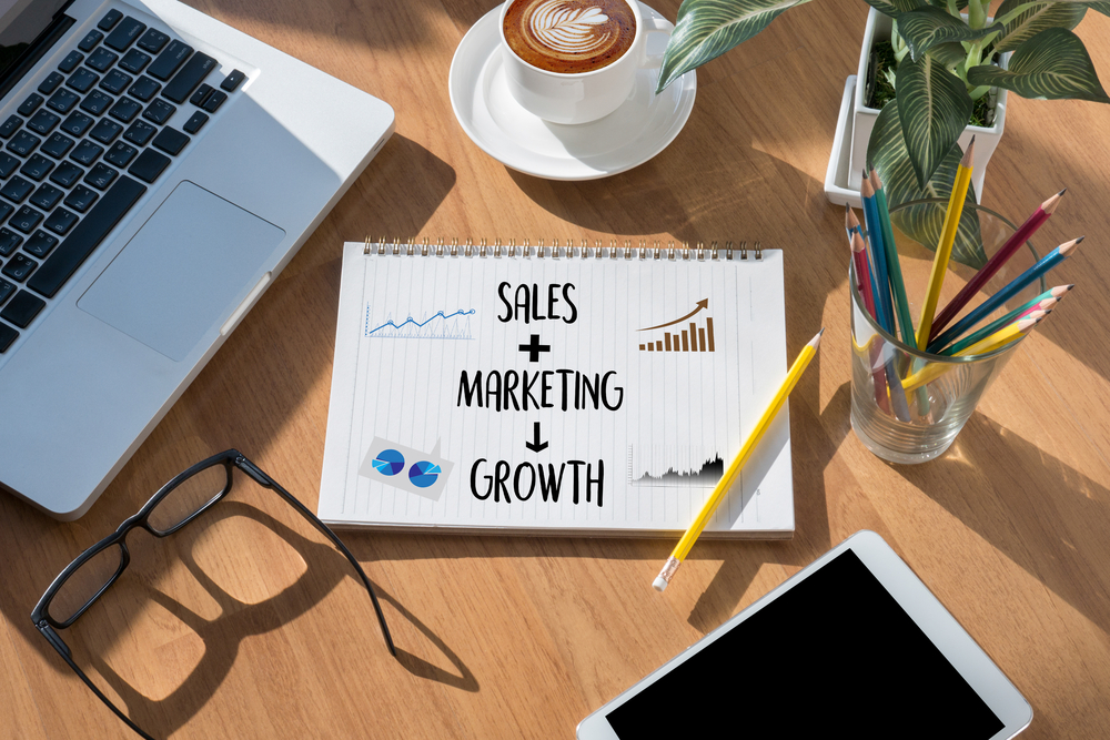notebook with written text that says sales, marketing, and growth