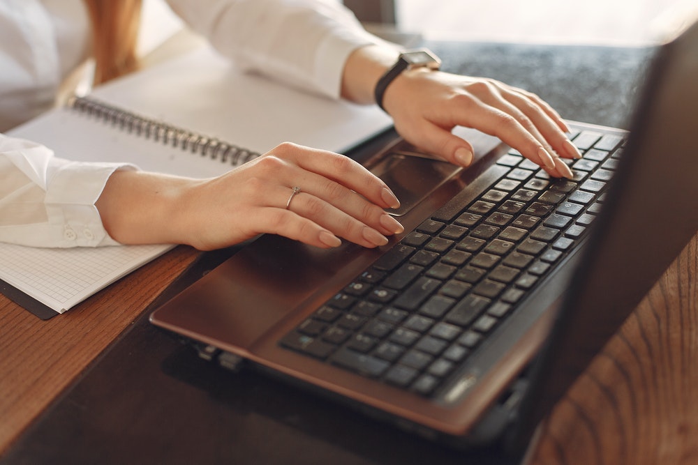 woman typing content on her laptop