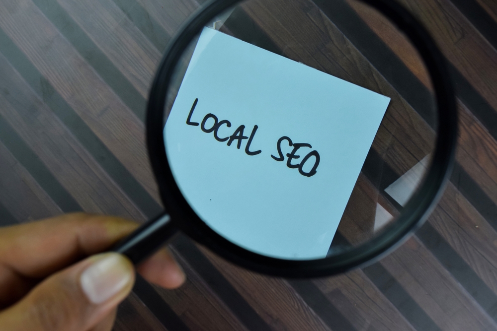hand holding a magnifying glass on top of a note that says local SEO