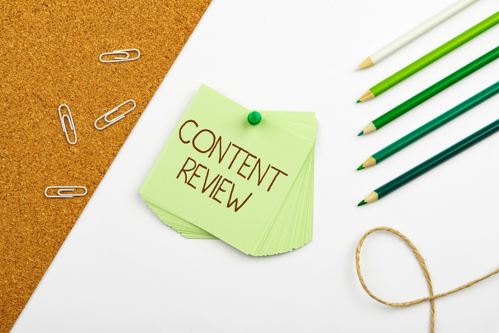 Content Review written on green sticky notes surrounded by paper clips and color pencils