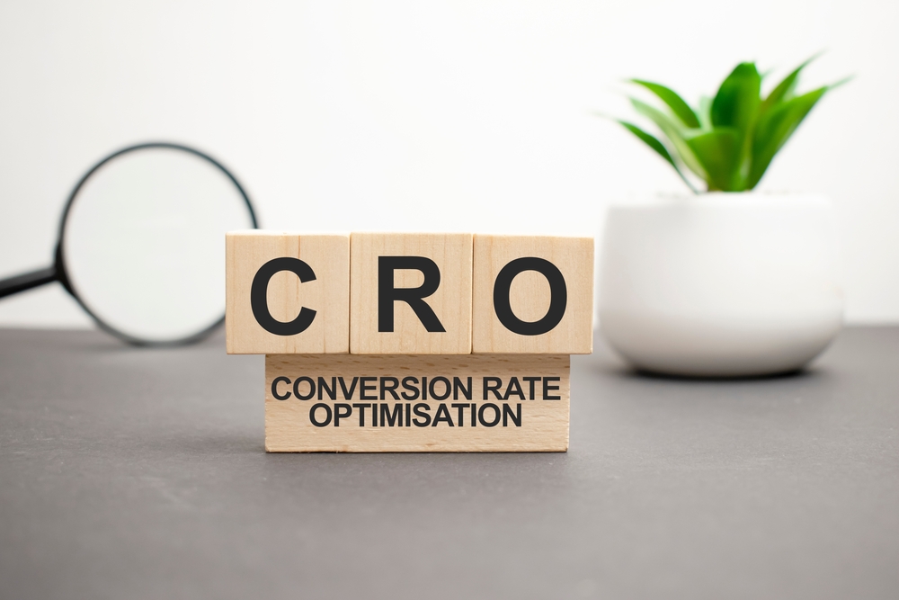 CRO Conversion Rate Optimization wooden blocks word on grey background with plant and magnifying glass