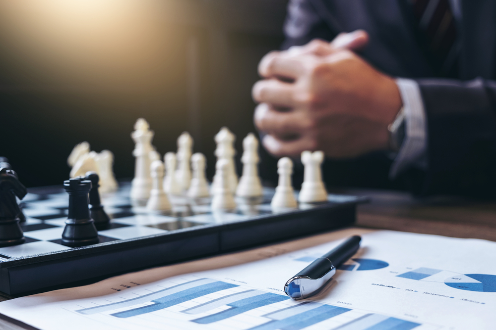 Close up of hands of a businessman playing chess competitve analysis concept
