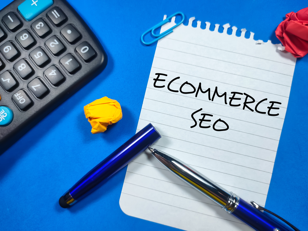 Ecommerce SEO written on white paper beside crumpled paper, calculator, and pen