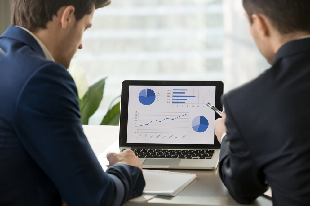 Rear view at two businessmen analyzing financial data on laptop screen