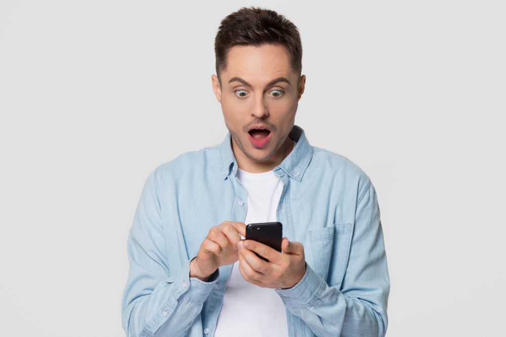 shocked guy holding a phone with white background