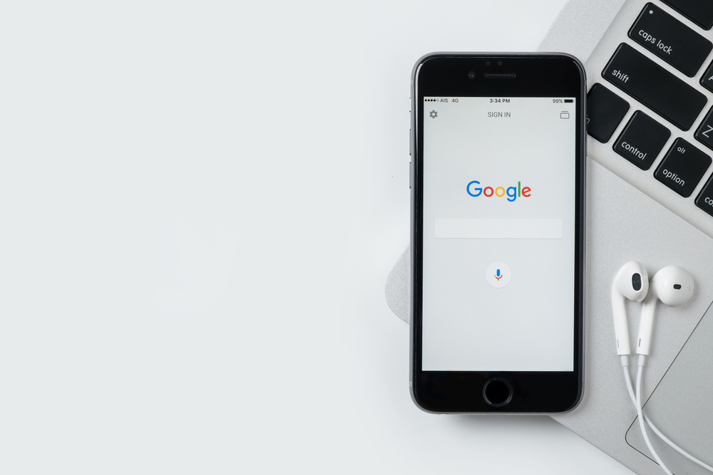 Google search voice on phone screen with laptop and earphone