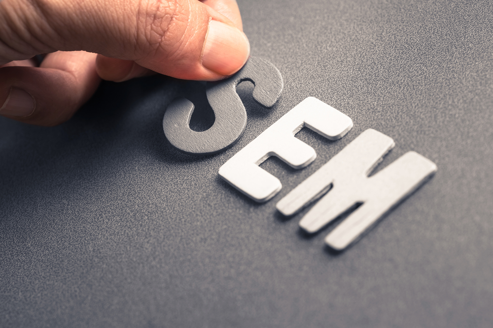 Closeup of a hand arranging sticker letters of SEM (Search Engine Marketing)
