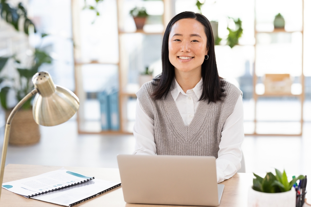 smiling Asian woman using a laptop in an office 